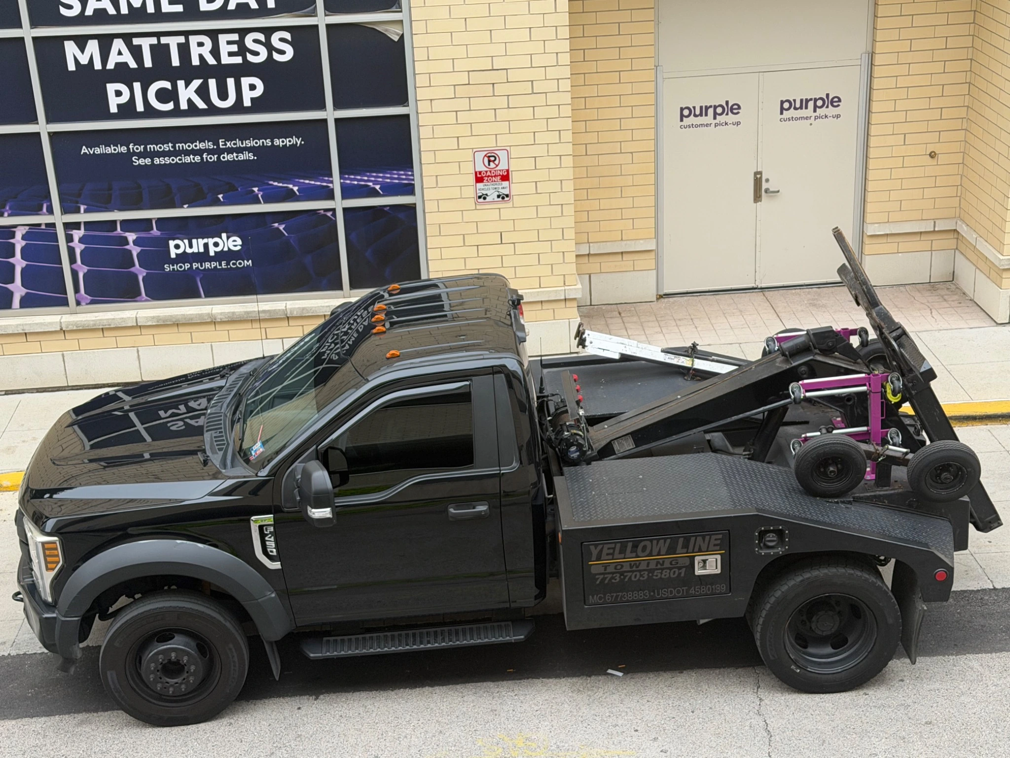 Exact photo of Yellow Line Towing's black 2018 Ford F-450 single-cab wheel-lift wrecker showing the Yellow Line Towing side-box branding